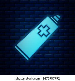 Glowing neon Ointment cream tube medicine icon isolated on brick wall background. Tube, container, toothpaste, cream sign.  Vector Illustration