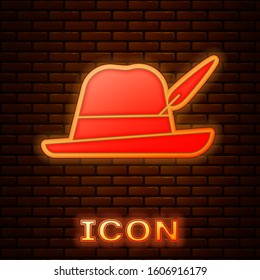 Glowing neon Oktoberfest hat icon isolated on brick wall background. Hunter hat with feather. German hat.  Vector Illustration