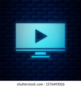 Glowing neon Online play video icon isolated on brick wall background. Computer monitor and film strip with play sign.  Vector Illustration