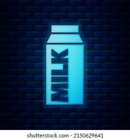 Glowing neon Paper package for milk icon isolated on brick wall background. Milk packet sign.  Vector