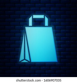Glowing neon Paper shopping bag icon isolated on brick wall background. Package sign.  Vector Illustration