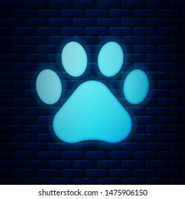 Glowing neon Paw print icon isolated on brick wall background. Dog or cat paw print. Animal track.  Vector Illustration