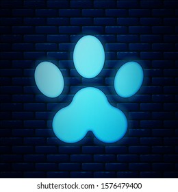 Glowing neon Paw print icon isolated on brick wall background. Dog or cat paw print. Animal track.  Vector Illustration