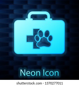 Glowing neon Pet first aid kit icon isolated on brick wall background. Dog or cat paw print. Clinic box. Vector Illustration