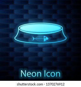 Glowing neon Pet food bowl for cat or dog icon isolated on brick wall background. Fish skeleton sign. Vector Illustration