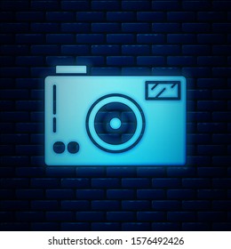 Glowing neon Photo camera icon isolated on brick wall background. Foto camera icon.  Vector Illustration