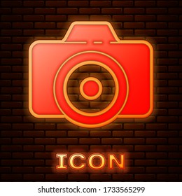 Glowing neon Photo camera icon isolated on brick wall background. Foto camera icon. Vector Illustration