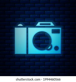 Glowing neon Photo camera icon isolated on brick wall background. Foto camera icon.  Vector