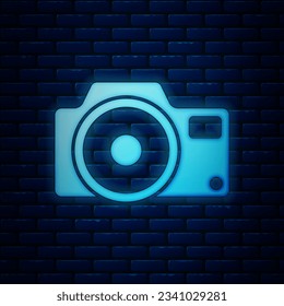 Glowing neon Photo camera icon isolated on brick wall background. Foto camera icon.  Vector