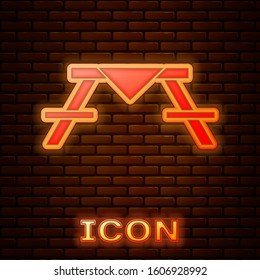 Glowing neon Picnic table with benches on either side of the table icon isolated on brick wall background.  Vector Illustration