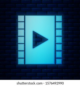 Glowing neon Play Video icon isolated on brick wall background. Film strip with play sign.  Vector Illustration