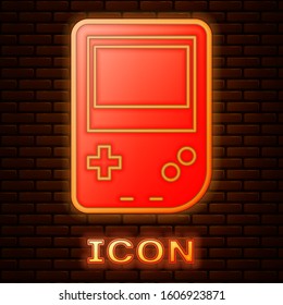 Glowing neon Portable video game console icon isolated on brick wall background. Gamepad sign. Gaming concept.  Vector Illustration
