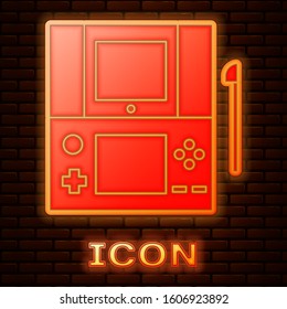 Glowing neon Portable video game console icon isolated on brick wall background. Gamepad sign. Gaming concept.  Vector Illustration