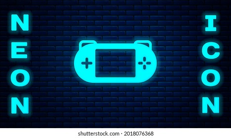 Glowing neon Portable video game console icon isolated on brick wall background. Gamepad sign. Gaming concept.  Vector