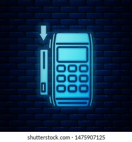 Glowing neon Pos terminal with inserted credit card icon isolated on brick wall background. Payment terminal transaction. Pay by card.  Vector Illustration