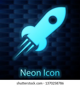 Glowing neon Rocket ship with fire icon isolated on brick wall background. Space travel. Vector Illustration