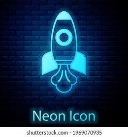 Icono del barco del neón Rocket brillante aislado en un fondo de pared de ladrillo. Viaje espacial.  Vector