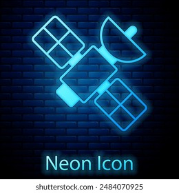 Glowing neon Satellite icon isolated on brick wall background.  Vector