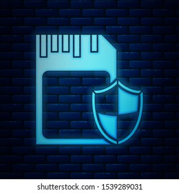 Glowing neon SD card and shield icon isolated on brick wall background. Memory card. Adapter icon. Security, safety, protection, privacy concept.  Vector Illustration