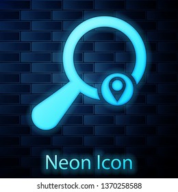 Glowing neon Search location icon isolated on brick wall background. Magnifying glass with pointer sign. Vector Illustration