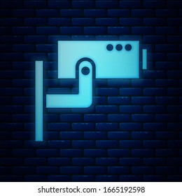 Glowing neon Security camera icon isolated on brick wall background.  Vector Illustration