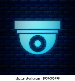Glowing neon Security camera icon isolated on brick wall background.  Vector