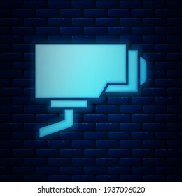 Glowing neon Security camera icon isolated on brick wall background.  Vector