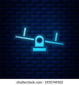 Glowing neon Seesaw icon isolated on brick wall background. Teeter equal board. Playground symbol.  Vector