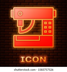 Glowing neon Sewing machine icon isolated on brick wall background.  Vector Illustration