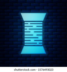 Glowing neon Sewing thread on spool icon isolated on brick wall background. Yarn spool. Thread bobbin.  Vector Illustration