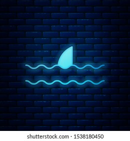 Glowing neon Shark fin in ocean wave icon isolated on brick wall background.  Vector Illustration