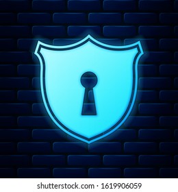 Glowing neon Shield with keyhole icon isolated on brick wall background. Protection and security concept. Safety badge icon. Privacy banner. Defense tag.  Vector Illustration