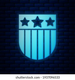 Glowing neon Shield with stars and stripes icon isolated on brick wall background. United States of America country flag. 4th of July. USA Independence day.  Vector