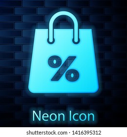 Glowing neon Shoping bag with an inscription percent discount icon isolated on brick wall background. Handbag sign. Woman bag icon. Female handbag sign. Vector Illustration
