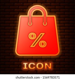 Glowing neon Shoping bag with an inscription percent discount icon isolated on brick wall background. Handbag sign. Woman bag icon. Female handbag sign.  Vector Illustration