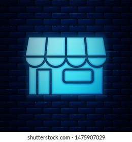 Glowing neon Shopping building or market store icon isolated on brick wall background. Shop construction.  Vector Illustration