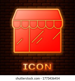 Glowing neon Shopping building or market store icon isolated on brick wall background. Shop construction. Vector