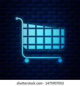Glowing neon Shopping cart icon isolated on brick wall background. Online buying concept. Delivery service sign. Supermarket basket symbol.  Vector Illustration