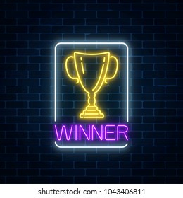 Glowing neon sign with award cup in rectangle frame on dark brick wall background. Winner cup honorary trophy neon symbol. Vector illustration.