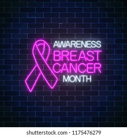 Glowing neon sign of breast canser awareness month in october. Neon poster design with pink ribbon and text on dark brick wall background. Vector illustration.