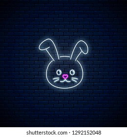 Glowing neon sign of cute rabbit in kawaii style on dark brick wall background. Cartoo happy smiling bunny in neon style. Vector illustration.