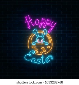 Glowing neon sign of easter bunny in basket with greeting inscription on dark brick wall background. Night greeting banner with easter rabbit. Vector illustration.