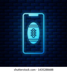 Glowing neon Smartphone with american football ball on the screen icon isolated on brick wall background. Online football game for mobile phone.  Vector Illustration