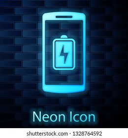 Glowing neon Smartphone battery charge icon isolated on brick wall background. Phone with a low battery charge. Vector Illustration