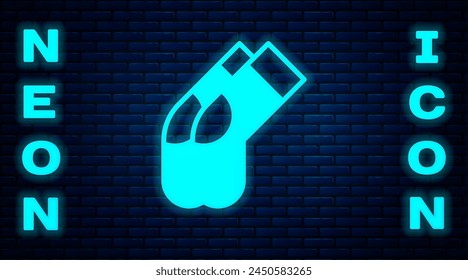 Icono de calcetines de neón brillante aislado en el fondo de la pared de ladrillo.  Vector