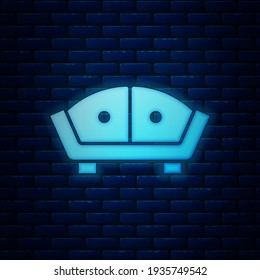 Icono de neón brillante Sofa aislado en el fondo de la pared de ladrillo.  Vector