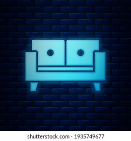 Icono de neón brillante Sofa aislado en el fondo de la pared de ladrillo.  Vector