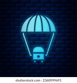 Glowing neon Space capsule returning to earth via parachute icon isolated on brick wall background.  Vector Illustration