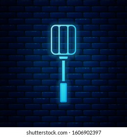 Glowing neon Spatula icon isolated on brick wall background. Kitchen spatula icon. BBQ spatula sign. Barbecue and grill tool.  Vector Illustration