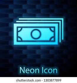 Glowing neon Stacks paper money cash icon isolated on brick wall background. Money banknotes stacks. Bill currency. Vector Illustration